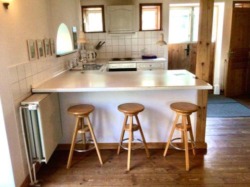 a kitchen with two bar stools and a counter at Hof Lücke - Ferienwohnung Blau in Twedt