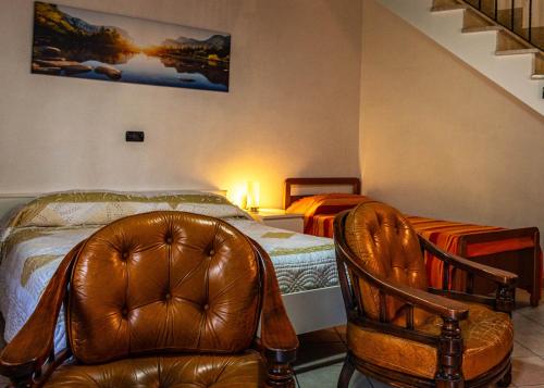 a bedroom with a bed and a leather chair and a chair at Casa Vacanze BELLO in Pietraroia