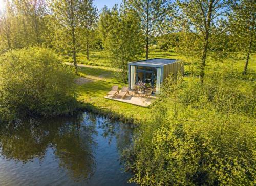 a tiny house in a field next to a river at Pean-buiten Cabins in Weidum