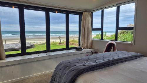 a bedroom with a bed and a view of the beach at Whareupoko in Waimarama