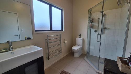 a bathroom with a shower and a sink and a toilet at Whareupoko in Waimarama