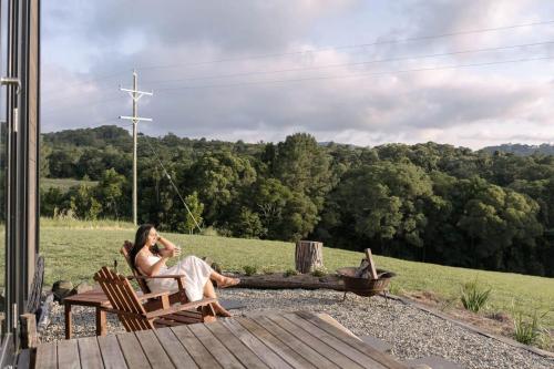 a woman sitting in a chair on a porch at Rainforest Sunsets by Tiny Away in Kuranda