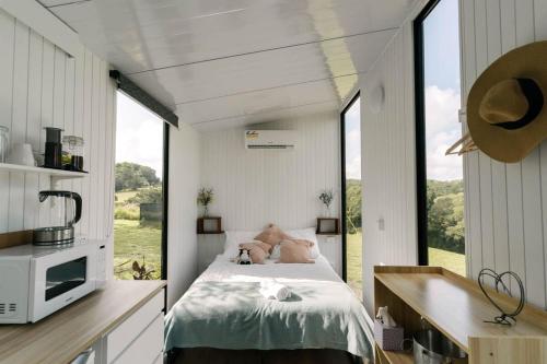a bedroom with a bed and a large window at Rainforest Sunsets by Tiny Away in Kuranda