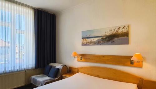 a hotel room with a bed and a chair and a window at Hotel Münchner Löwenbräu in Cuxhaven