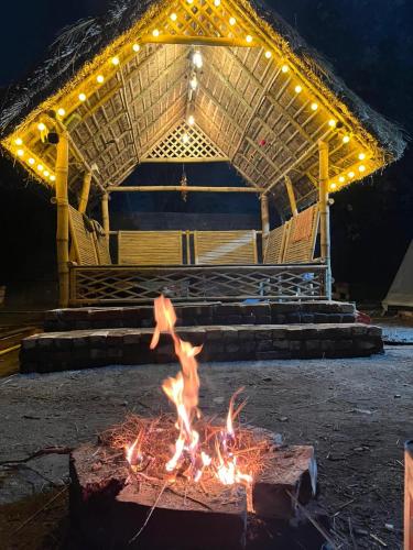 a fire pit in front of a stage with lights at Canopy Haven in Siliguri