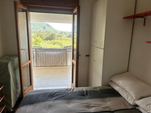 a bedroom with a bed and a door to a balcony at Casa COMER GRISOLIA in Cirella