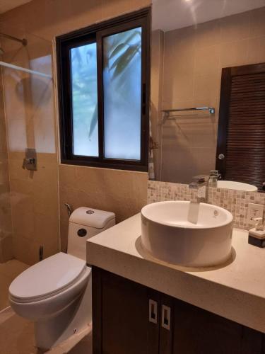 a bathroom with a sink and a toilet and a window at Apartment Eliza Samui in Garden Resort with Shared Pool in Plai Laem