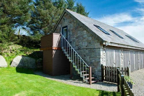 a small stone building with a staircase next to a house at Dartmoor Barn on North Hessary Tor in Yelverton