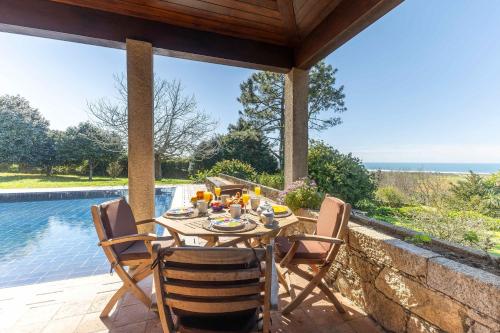 a table and chairs on a patio next to a pool at Carreços Beach Farm in Viana do Castelo