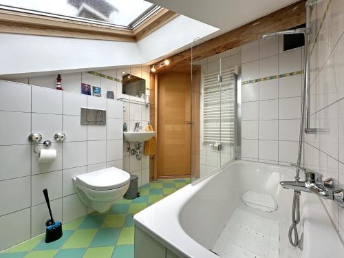 a bathroom with a tub and a toilet at Ferienwohnung Scheibenwand-Loft in Aschau im Chiemgau