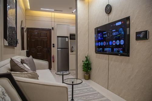 a living room with a couch and a tv on a wall at أجنحة لوسيل 3 Lucille Suites in Jeddah