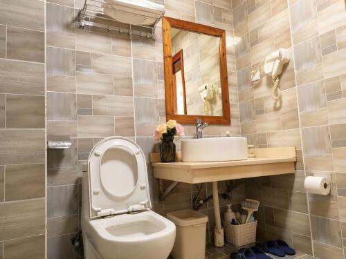 a bathroom with a toilet and a sink and a mirror at 八零年代客栈 in Hanqiyu
