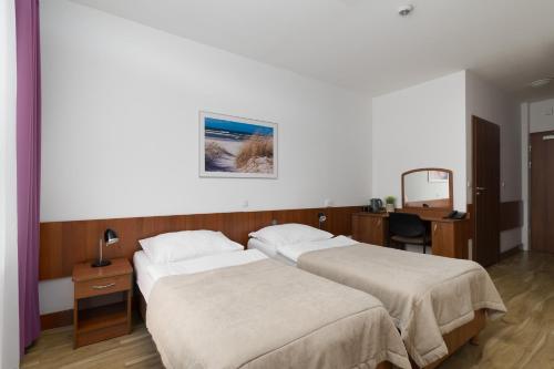 a bedroom with two beds and a desk with a mirror at San Medical Spa in Kołobrzeg