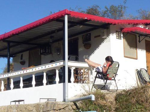 a woman sitting in a chair in front of a house at Dhanaulti Camp Homes Retreat in Dhanaulti
