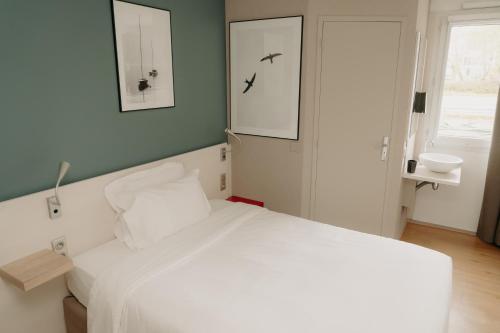 a bedroom with a white bed and a window at Kyriad Quimper Sud in Quimper
