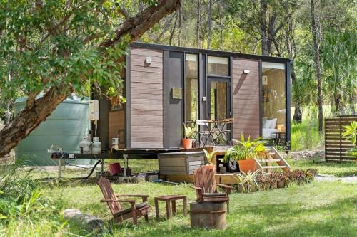 a tiny house in a yard with chairs at Wildlife Haven by Tiny Away in Agnes Water