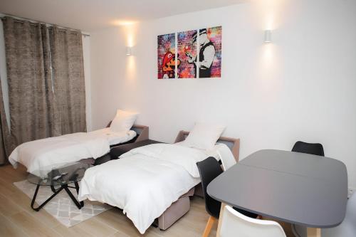 a room with three beds and a table at Grand T2 proche Créteil Soleil et Métro in Créteil