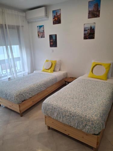 two beds with yellow pillows in a room at Lisbon south side apartments in Barreiro