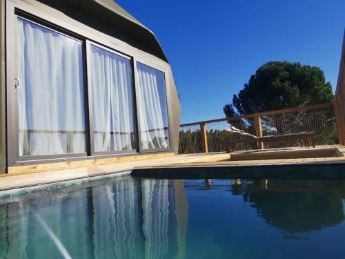 a swimming pool in front of a house with windows at Quinta das Pinheirinhas in Tomar