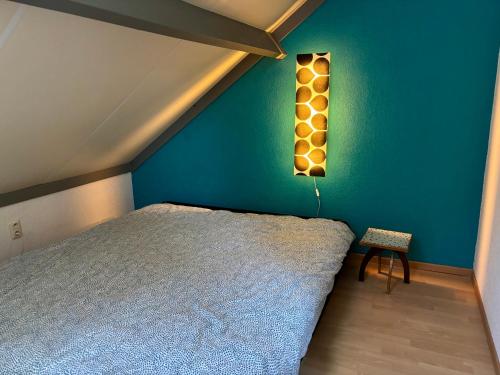 a bedroom with a bed and a blue wall at House & garden l'Hippodrome in Bredene