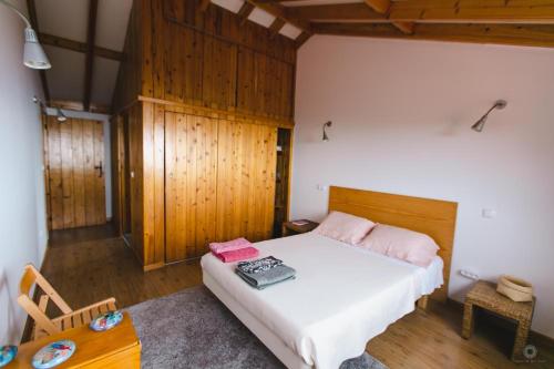 a bedroom with a white bed and a table at Casa da Petra in Urzelina