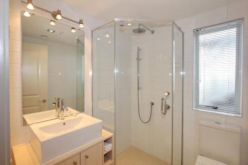 a bathroom with a sink and a shower with a glass door at Crow's Nest Apartments in Whitianga