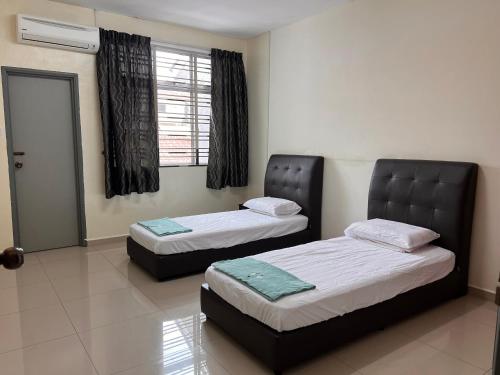 two beds sitting in a room with a window at Homestay 76 in Mersing