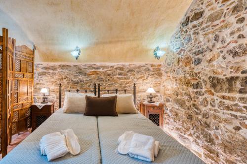 a bedroom with a bed and a stone wall at Mesaionas 1 in Olýmpoi