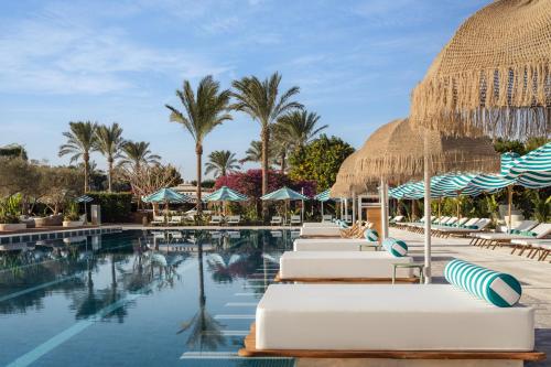 a resort pool with lounge chairs and umbrellas at Desert Rose in Hurghada