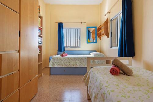 a bedroom with two beds with blue curtains at Finca El Pizarro in Arico