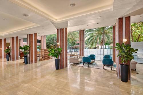 a lobby with chairs and plants in a building at Sheraton Skyline Hotel London Heathrow in Hillingdon