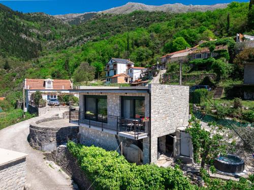 a stone house on a hill with mountains in the background at Dream View Villa in Kotor