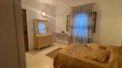 a bedroom with a bed and a bathroom with a sink at Ali yessine in Al Maqārisah