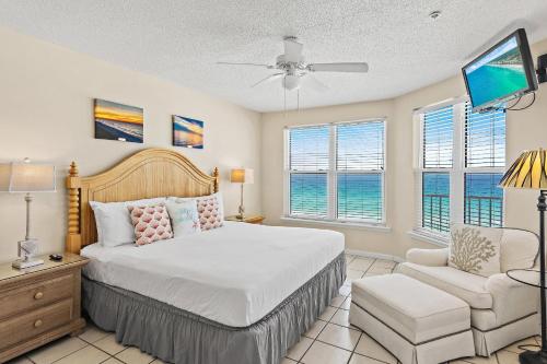 a bedroom with a bed and a chair and windows at The Palms #601 in Fort Walton Beach