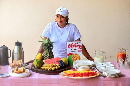 a woman standing in front of a table with food at Moshono WiDa Lodge in Arusha