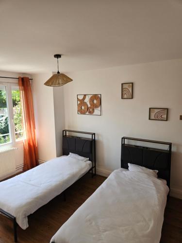 two beds in a room with a window at Gite Les 4 Fleurs in Le Puy-en-Velay