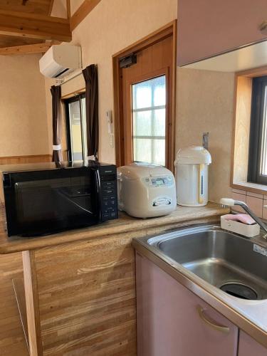 a kitchen with a microwave and a sink at Katamaeyama Forest Park Cottage TypeC in Senboku