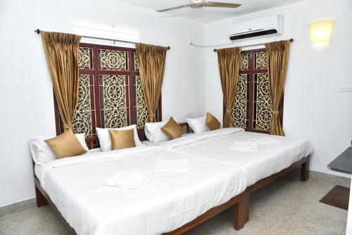 a large white bed in a room with windows at La Maison Mira in Pondicherry