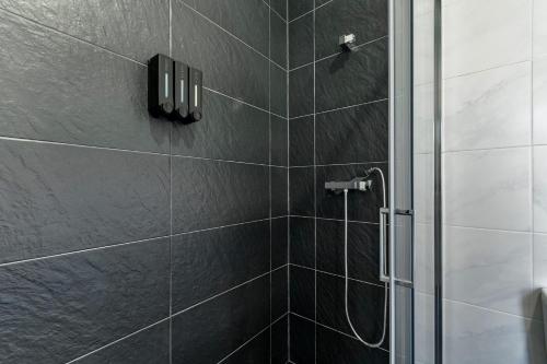 a bathroom with a shower with black tiles at Casa do Recanto - Loriga - Serra da Estrela in Loriga