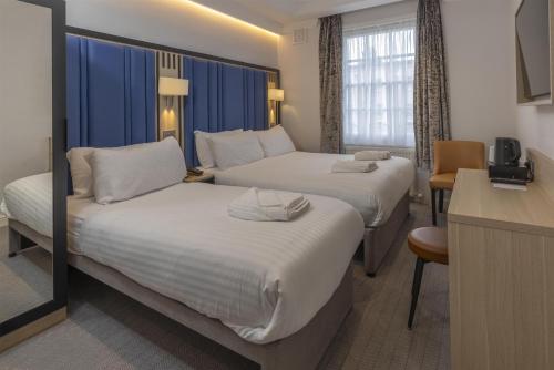 a hotel room with two beds and a table at Best Western Victoria Palace in London