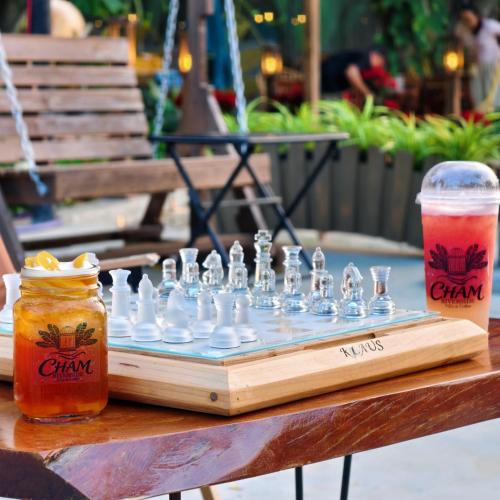 a wooden chess board with chess pieces and drinks on a table at Cham Riverside in Thôn Xuân Lạc