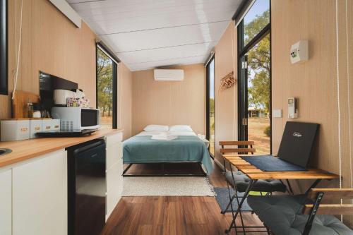 a room with a bed and a desk with a laptop at Kiara By Tiny Away in Stawell