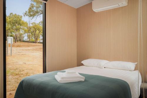 a bed in a room with a window with towels on it at Kiara By Tiny Away in Stawell