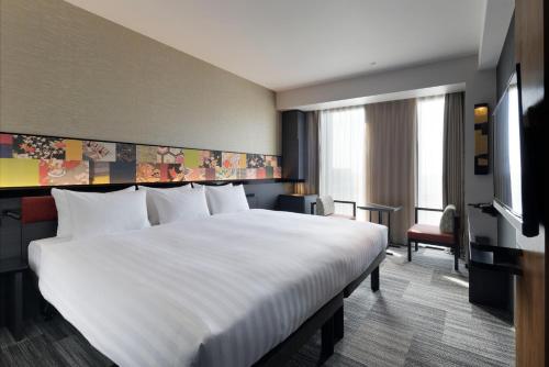 a hotel room with a large bed and a tv at Mitsui Garden Hotel Kanazawa in Kanazawa