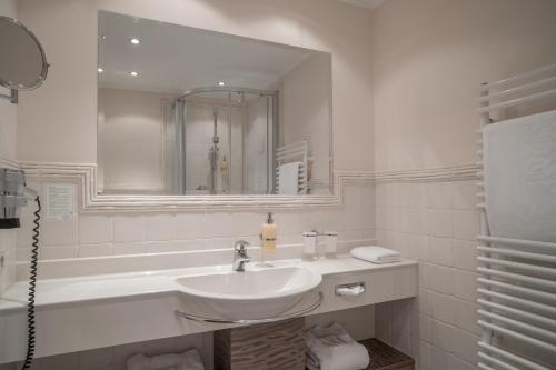 a white bathroom with a sink and a tub at Hotel Madeleine in Obergurgl