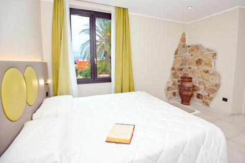 a book on a white bed in a room with a window at Hotel Corallo New in Muravera