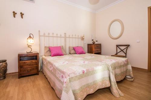 a bedroom with a large bed with pink pillows at Quinta das Yuccas by Algarve Holidays in Boliqueime
