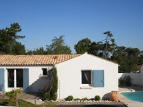 une maison blanche avec une piscine en face de celle-ci dans l'établissement Les Dunes Oleron, à Grand-Village-Plage