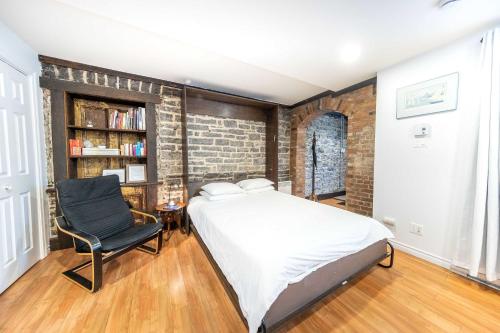 a bedroom with a bed and a chair and a brick wall at Near the Ferry - Studio de charme in Lévis