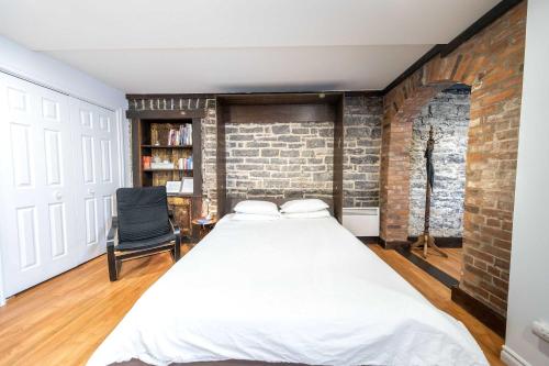 a bedroom with a bed and a brick wall at Near the Ferry - Studio de charme in Lévis